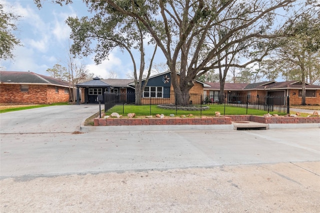 ranch-style house with a front yard, a fenced front yard, concrete driveway, and brick siding