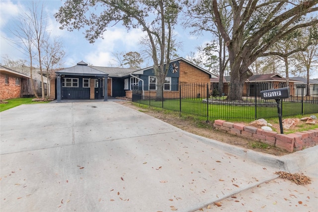 view of front of house featuring concrete driveway, a front yard, brick siding, and a fenced front yard