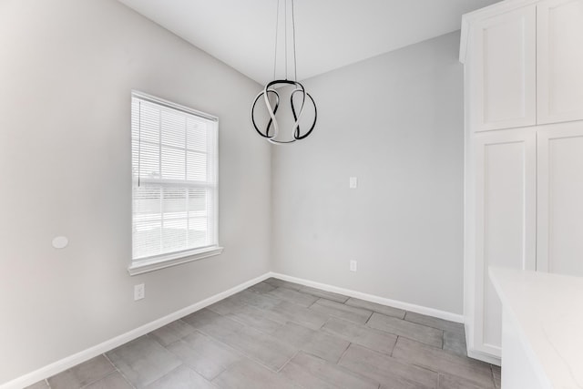 unfurnished dining area featuring baseboards and an inviting chandelier