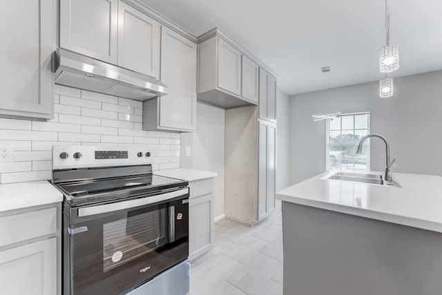 kitchen with under cabinet range hood, light countertops, a sink, and stainless steel range with electric cooktop
