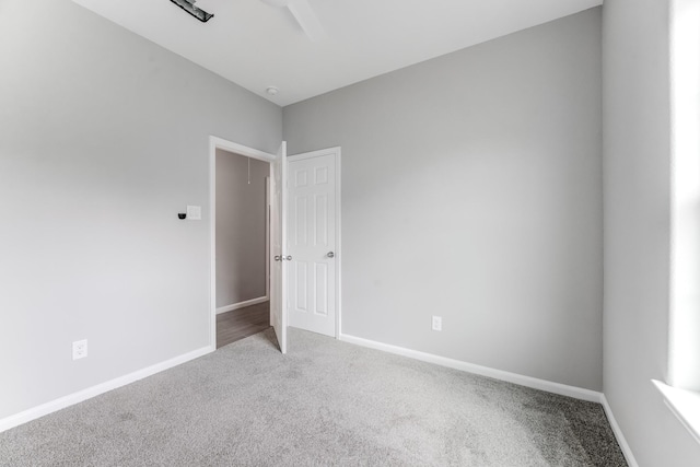 carpeted spare room with baseboards and a ceiling fan