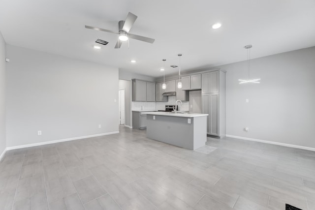 kitchen with open floor plan, light countertops, gray cabinetry, backsplash, and a ceiling fan