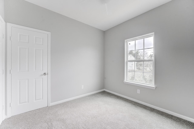carpeted empty room featuring baseboards