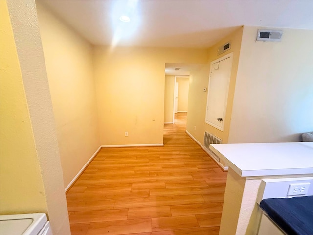 corridor featuring light wood finished floors, baseboards, and visible vents