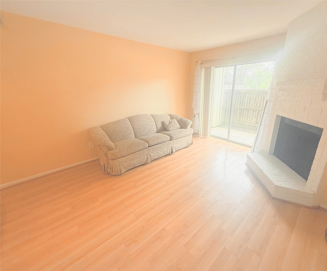 unfurnished living room featuring a brick fireplace, baseboards, and light wood-style floors