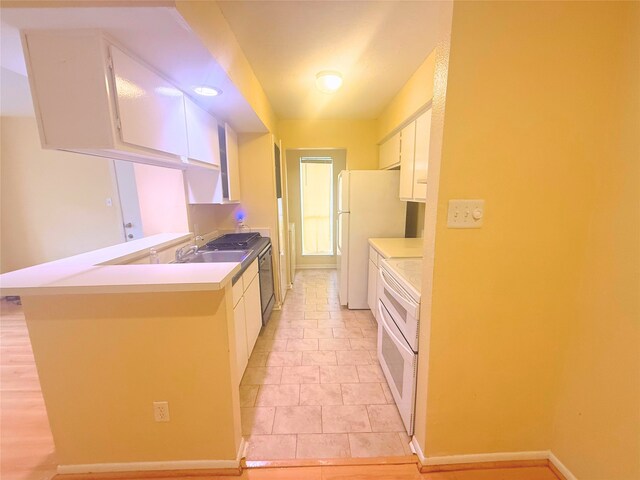 kitchen featuring light countertops, white cabinets, a peninsula, and white appliances