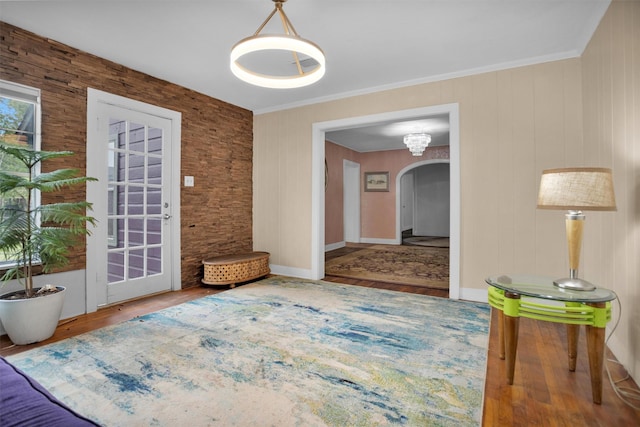 interior space featuring ornamental molding, arched walkways, and wood finished floors