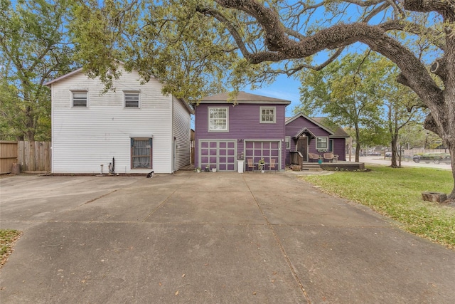 view of front of house with concrete driveway, a garage, fence, and a front lawn
