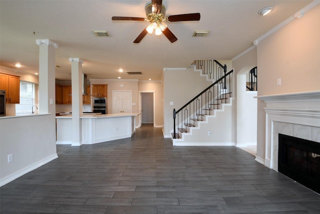18719 Racquet Sports Way, Humble, TX 77346 - unfurnished living room featuring dark wood finished floors, ceiling fan, crown molding, a tiled fireplace, and stairway