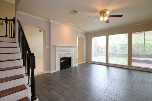 18719 Racquet Sports Way, Humble, TX 77346 - unfurnished living room featuring ceiling fan, arched walkways, healthy amount of natural light, ornamental molding, and a tile fireplace