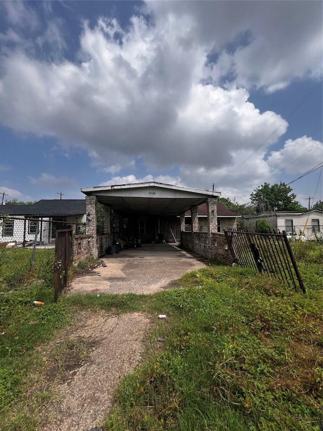 rear view of property featuring an attached carport, driveway, and fence