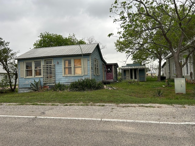 bungalow-style house featuring a front yard and metal roof