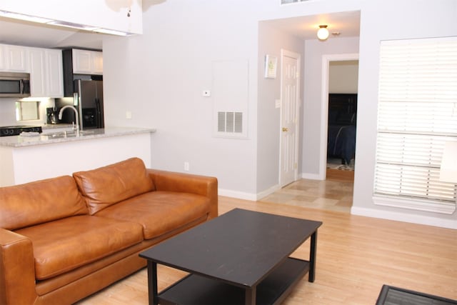 living room featuring light wood finished floors, baseboards, and visible vents