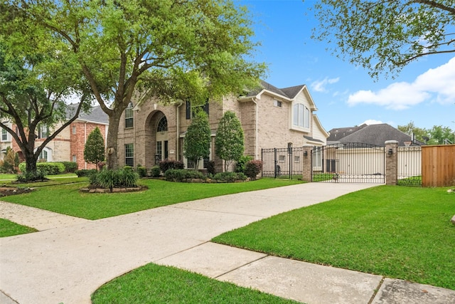 view of front of house featuring brick siding, fence, a front lawn, and a gate