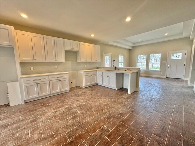 9830 Turnbow St, Houston, TX 77029 - kitchen featuring white cabinets, a peninsula, tasteful backsplash, and a tray ceiling