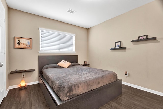 bedroom with wood finished floors, visible vents, and baseboards