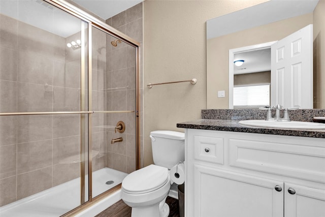 bathroom featuring vanity, a shower stall, and toilet