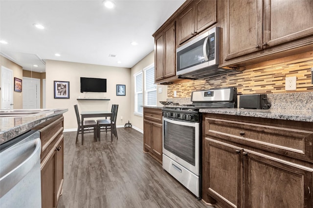 kitchen with baseboards, backsplash, appliances with stainless steel finishes, and dark wood finished floors