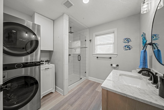 1407 John St, San Leon, TX 77539 - full bath with stacked washer / dryer, a shower stall, baseboards, wood finished floors, and vanity