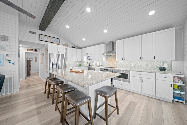 1407 John St, San Leon, TX 77539 - kitchen featuring wall chimney exhaust hood, stainless steel appliances, a breakfast bar area, a sink, and light wood-type flooring
