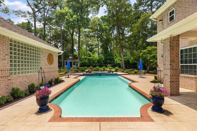 view of swimming pool with a patio area, a pool with connected hot tub, and fence