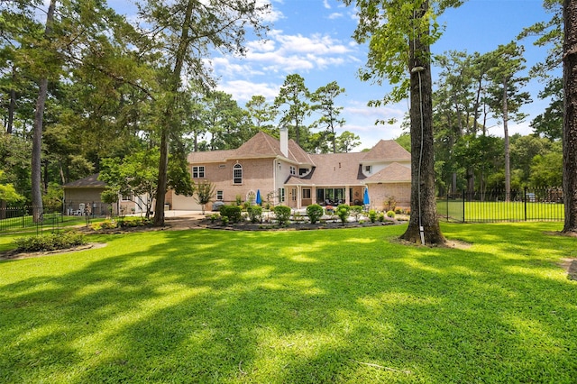 rear view of house with fence, a lawn, and a chimney