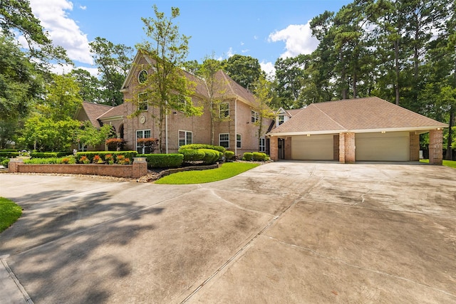 view of front of home featuring an attached garage, roof with shingles, driveway, and brick siding