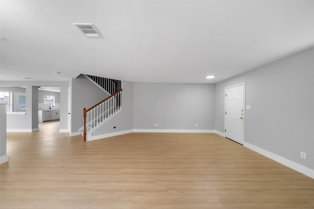 6718 Wild Pecan Trl, Houston, TX 77084 - unfurnished living room with light wood-style flooring, baseboards, visible vents, recessed lighting, and stairs