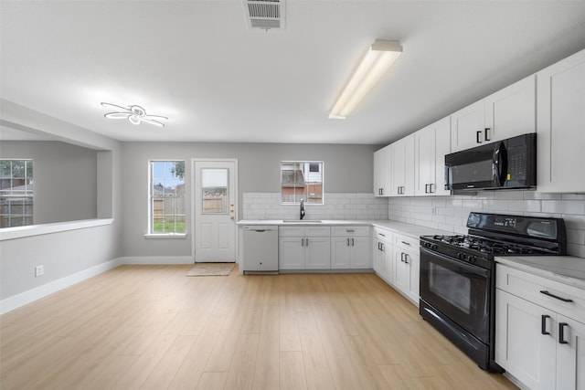 6718 Wild Pecan Trl, Houston, TX 77084 - kitchen with light countertops, a sink, black appliances, tasteful backsplash, and white cabinetry