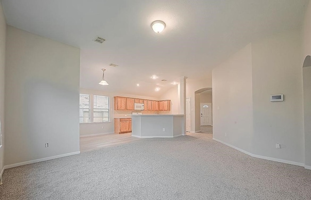 18918 Knobby Oaks Pl, Magnolia, TX 77355 - unfurnished living room featuring arched walkways, light carpet, baseboards, lofted ceiling, and decorative columns