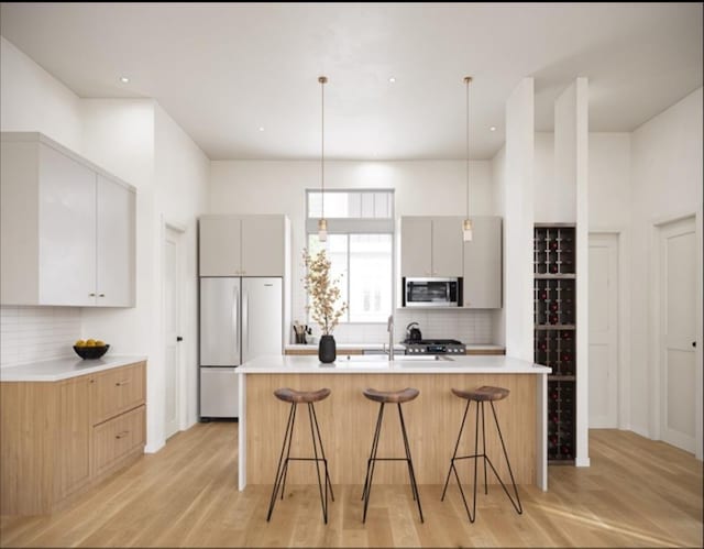 kitchen with gray cabinets, tasteful backsplash, stainless steel appliances, and a breakfast bar