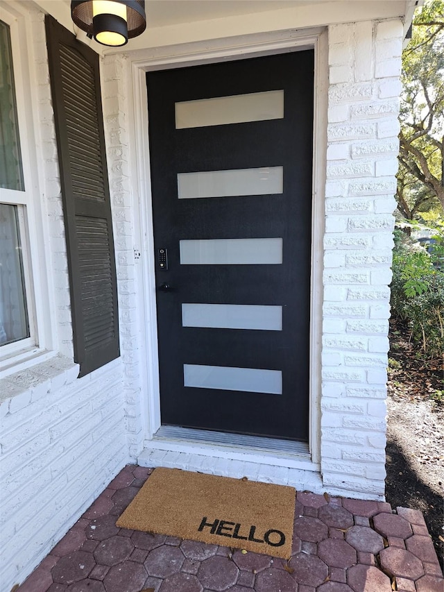 view of exterior entry featuring brick siding