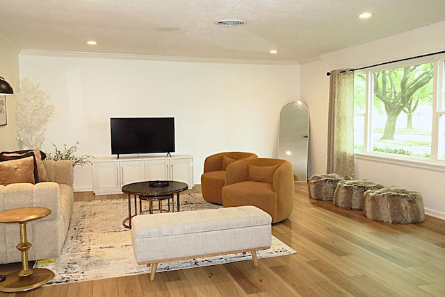 living area featuring light wood finished floors, a wealth of natural light, and crown molding