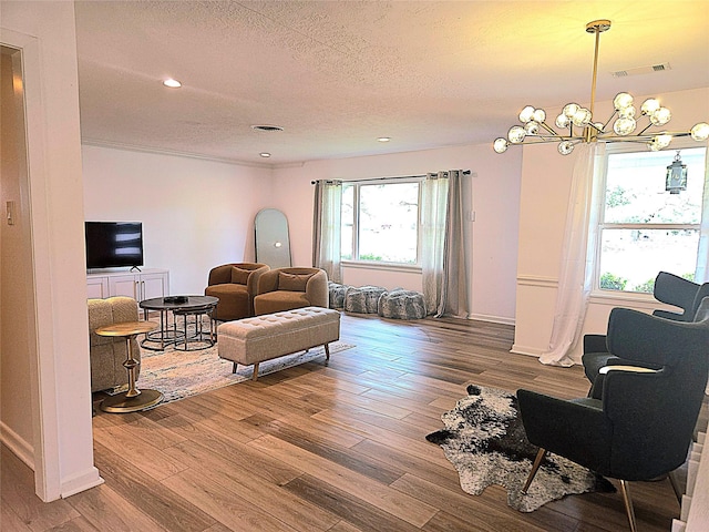 living area featuring wood finished floors, visible vents, and a notable chandelier