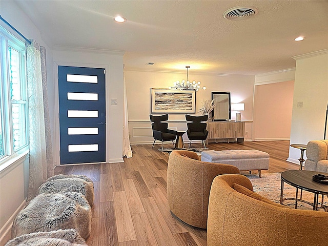 living area with a notable chandelier, crown molding, visible vents, and light wood-type flooring