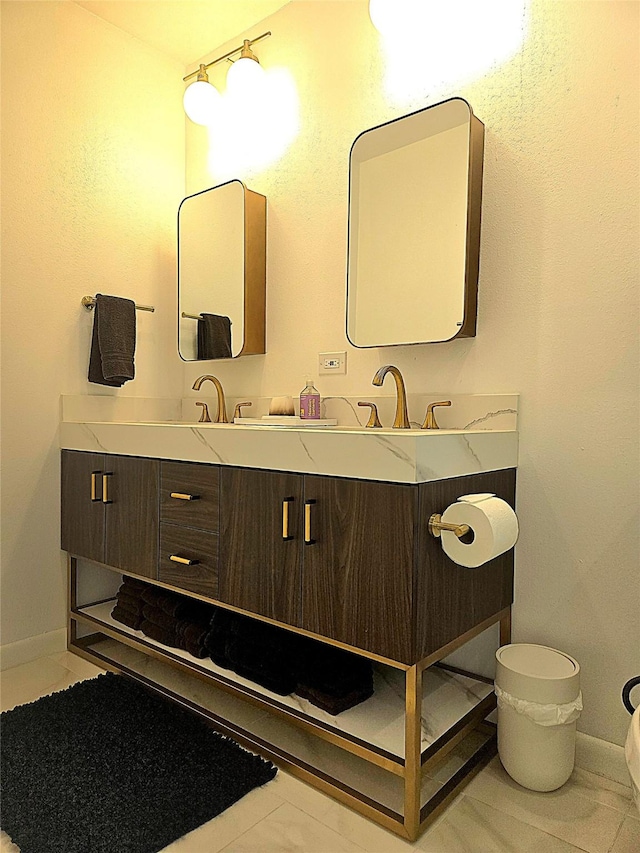 bathroom with baseboards, a sink, and double vanity