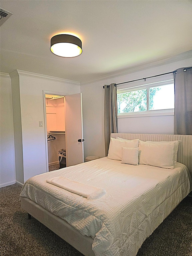 bedroom featuring carpet flooring, baseboards, visible vents, a spacious closet, and ornamental molding