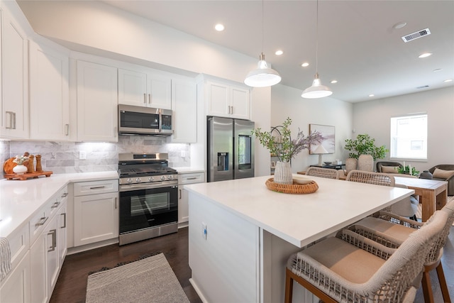 kitchen with a kitchen breakfast bar, visible vents, decorative backsplash, appliances with stainless steel finishes, and white cabinetry