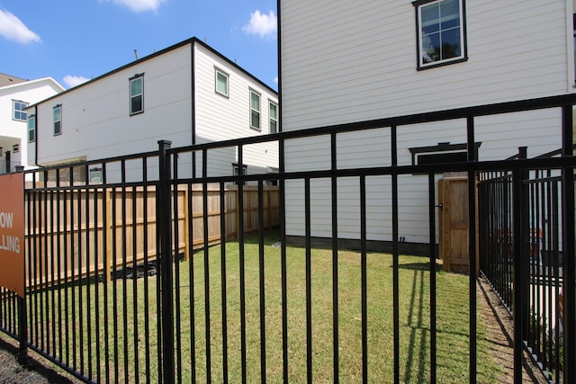view of gate featuring a lawn and a fenced backyard