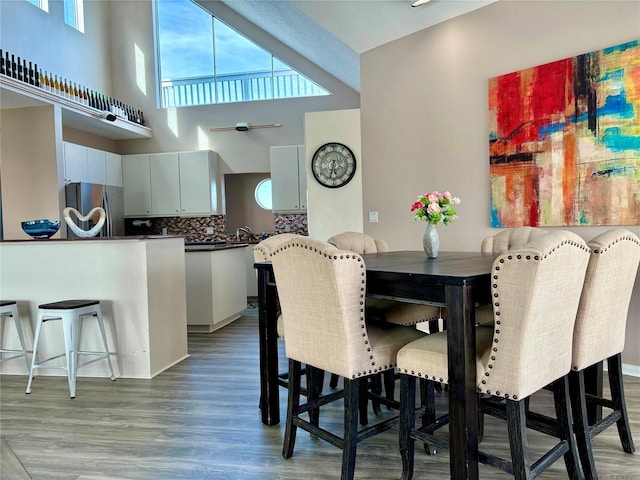 dining area featuring a towering ceiling and light wood-style flooring