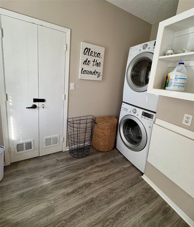 laundry area featuring visible vents, stacked washer / drying machine, laundry area, and dark wood-style flooring