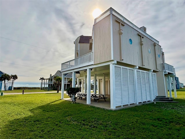 rear view of property featuring a balcony, a patio, and a yard