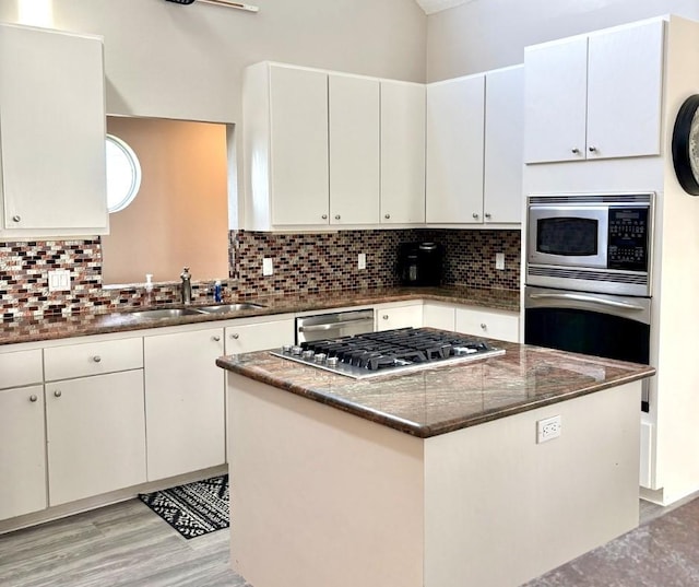 kitchen featuring appliances with stainless steel finishes, tasteful backsplash, dark stone countertops, and a sink