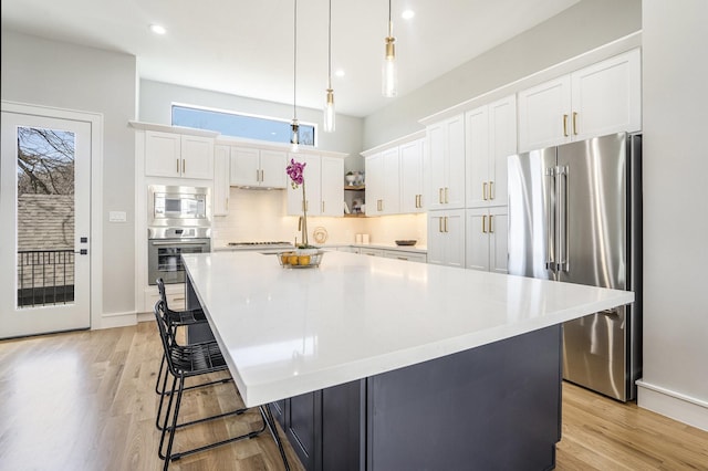 2218 Francis St, Houston, TX 77004 - kitchen with pendant lighting, white cabinets, appliances with stainless steel finishes, a center island, and light wood finished floors