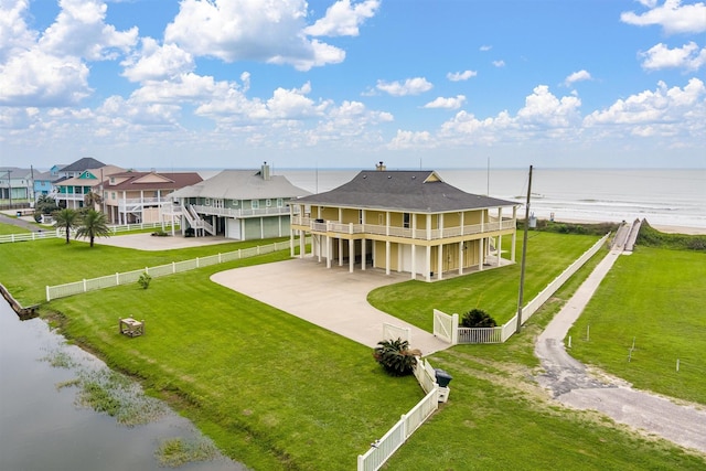 back of house featuring a fenced backyard, a lawn, driveway, and a water view