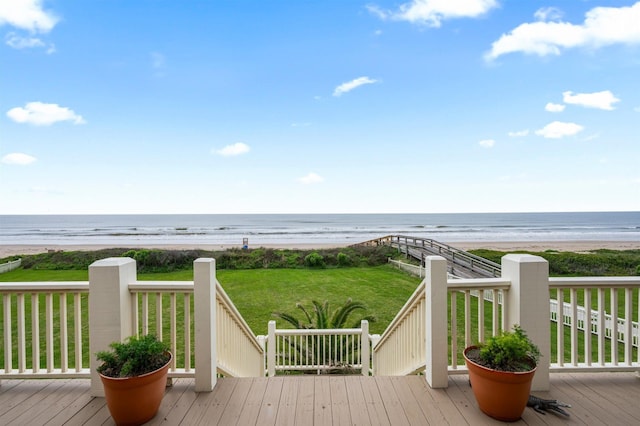 deck with a yard, a water view, and a beach view