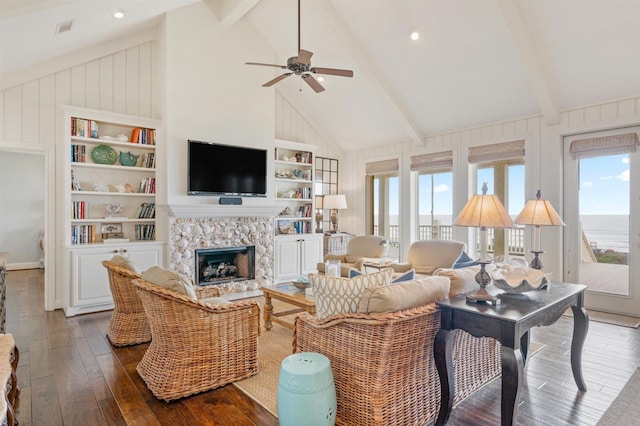 living area with a ceiling fan, beam ceiling, a healthy amount of sunlight, and dark wood finished floors