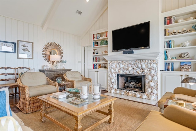 living room featuring lofted ceiling with beams, wood finished floors, a high end fireplace, built in features, and visible vents