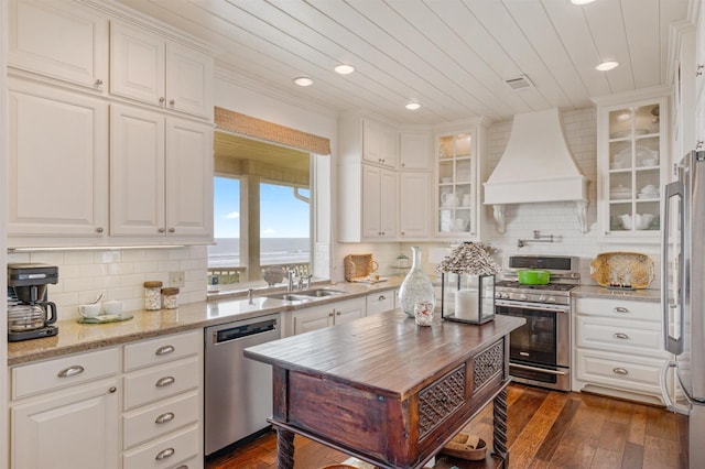 kitchen with white cabinets, a sink, custom exhaust hood, and appliances with stainless steel finishes
