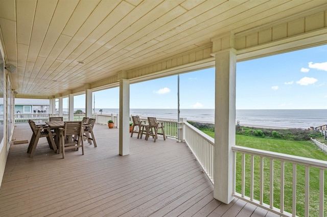 deck with a view of the beach, outdoor dining space, and a water view